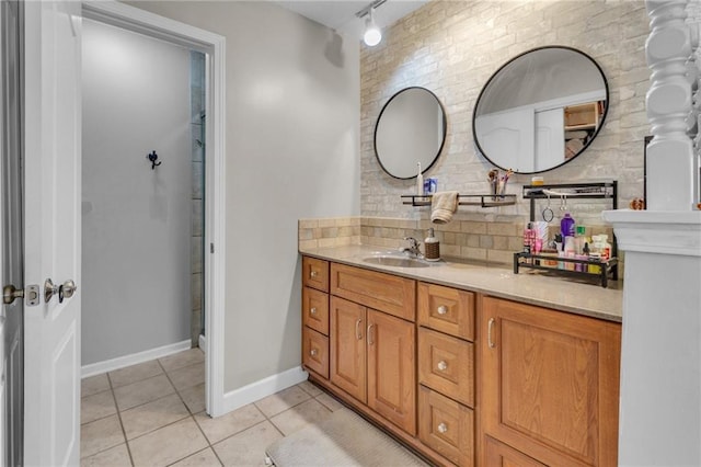 bathroom featuring track lighting, brick wall, tile patterned flooring, baseboards, and vanity