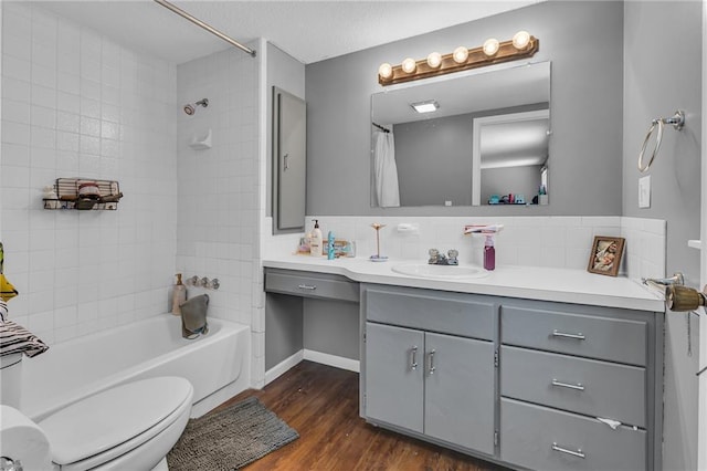 bathroom with vanity, wood finished floors, decorative backsplash, shower / bath combo with shower curtain, and toilet