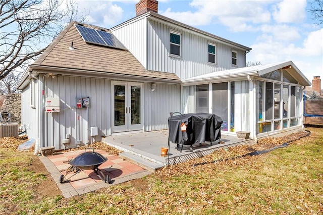 back of property featuring a patio, a sunroom, a chimney, a fire pit, and french doors