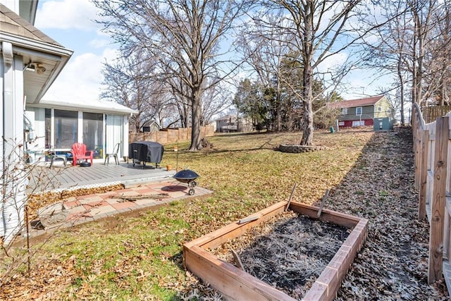 view of yard with a vegetable garden, fence, and a sunroom