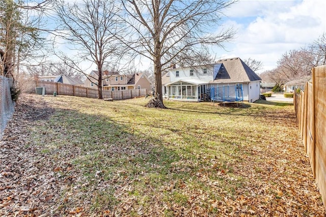 view of yard with a fenced backyard, a trampoline, and a sunroom