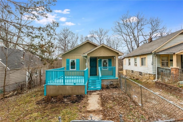 view of front of home with board and batten siding, covered porch, and fence