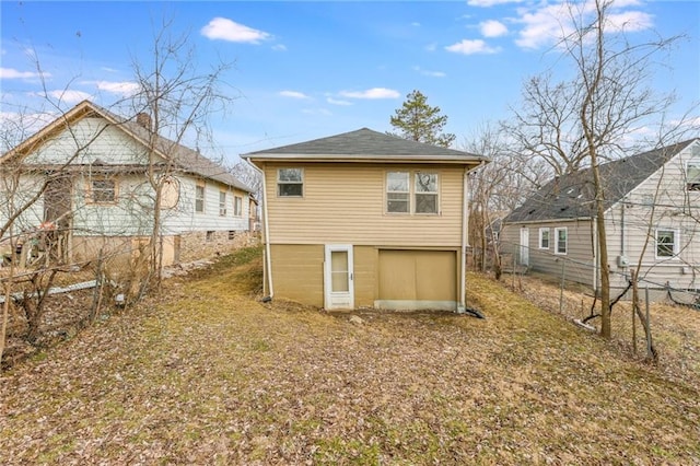 rear view of property with driveway, an attached garage, and fence