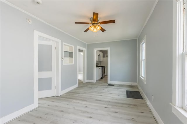 spare room with baseboards, light wood-style floors, ornamental molding, and a ceiling fan