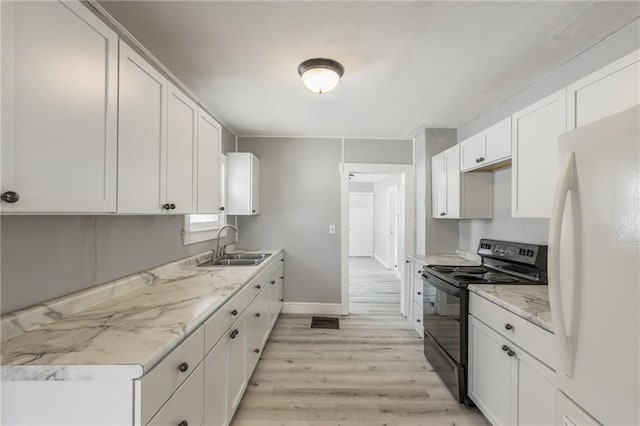 kitchen featuring freestanding refrigerator, a sink, black range with electric cooktop, light wood-style floors, and white cabinetry