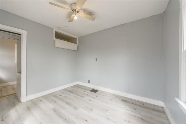 spare room with a ceiling fan, light wood-type flooring, and baseboards