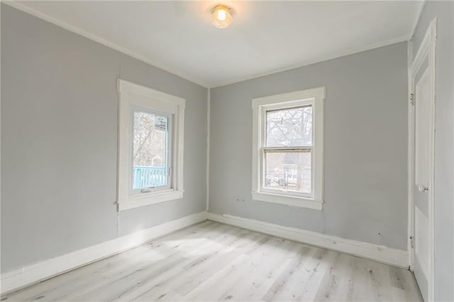 unfurnished room with baseboards, plenty of natural light, crown molding, and light wood finished floors