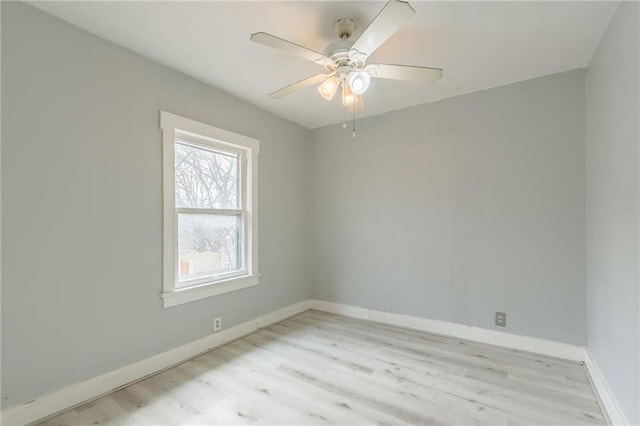 spare room with baseboards, wood finished floors, and a ceiling fan