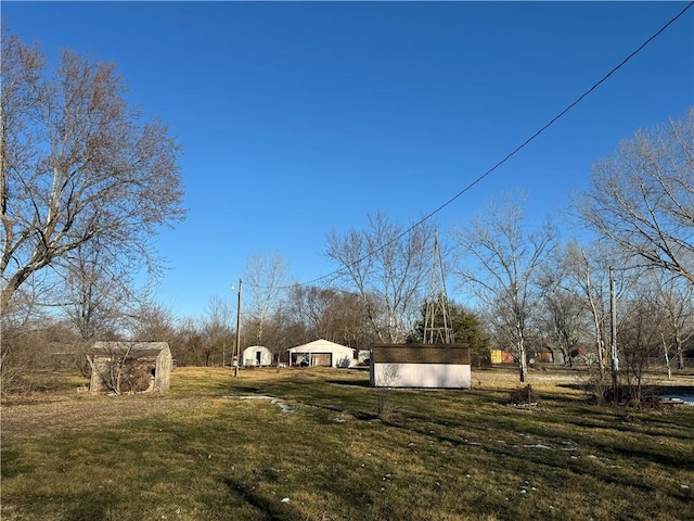 view of yard with a rural view, a storage unit, a detached garage, and an outdoor structure