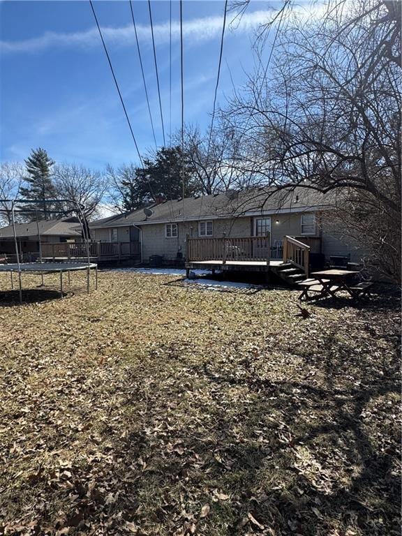 rear view of property featuring a wooden deck and a trampoline