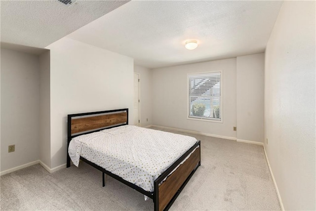 bedroom with light colored carpet, baseboards, and a textured ceiling