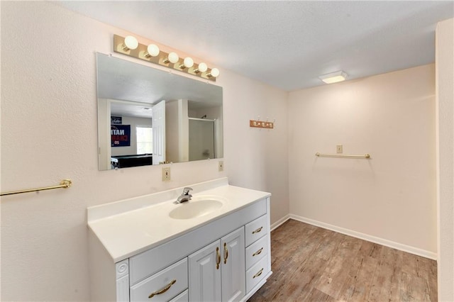 full bath featuring baseboards, a stall shower, wood finished floors, a textured ceiling, and vanity