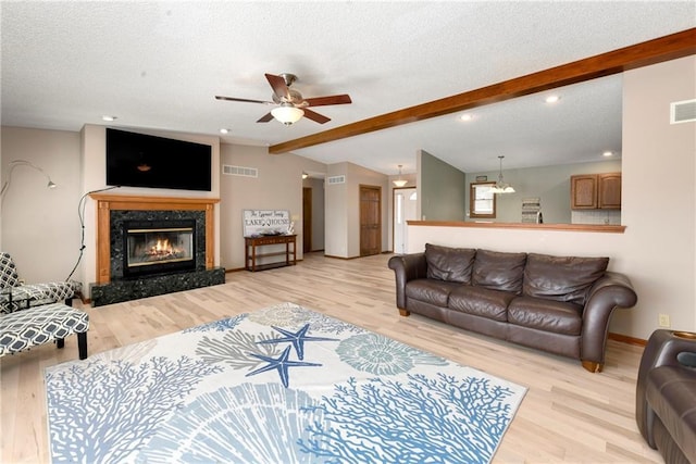 living room with lofted ceiling with beams, a premium fireplace, a textured ceiling, and light wood finished floors