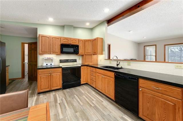 kitchen featuring a sink, dark countertops, black appliances, and vaulted ceiling with beams