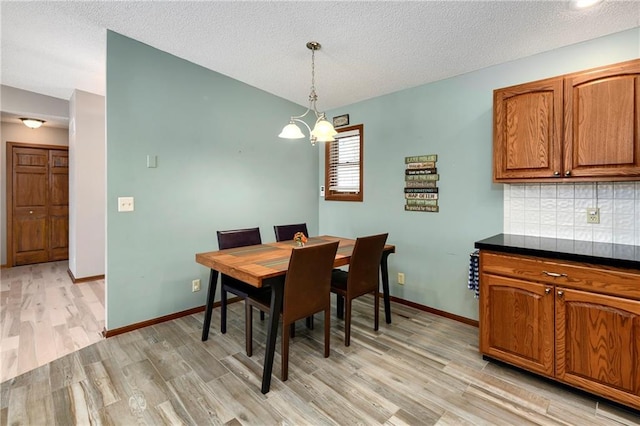 dining space featuring baseboards, lofted ceiling, and light wood finished floors