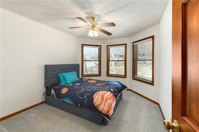 carpeted bedroom featuring ceiling fan, a textured ceiling, and baseboards