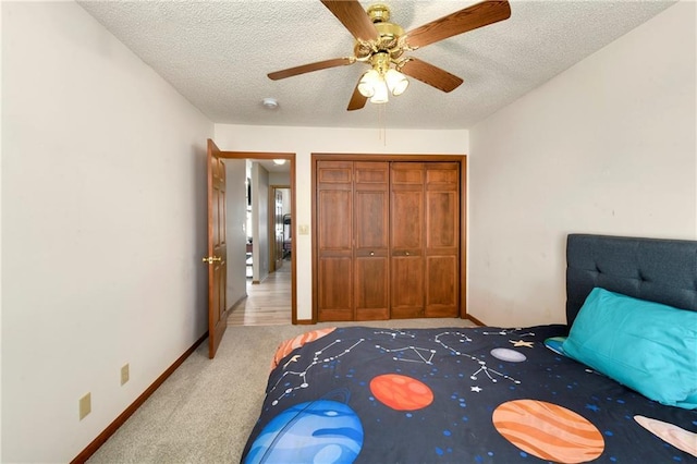 unfurnished bedroom featuring a textured ceiling, a closet, carpet floors, baseboards, and ceiling fan