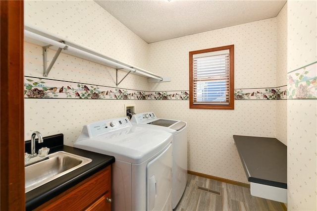 laundry area with a sink, separate washer and dryer, and wallpapered walls