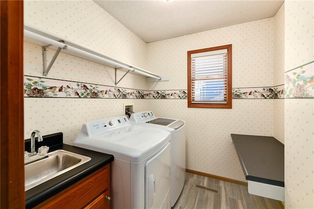 106 Timber Valley Dr, Linn Valley, KS 66040 - clothes washing area featuring light wood-style floors, wallpapered walls, separate washer and dryer, a sink, and cabinet space