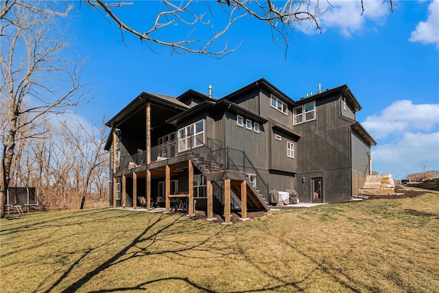 rear view of property featuring a wooden deck, a lawn, and stairs