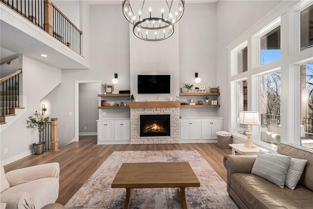 21143 W 189th Ct, Spring Hill, KS 66083 - living room featuring a towering ceiling, light wood-type flooring, a stone fireplace, stairway, and a chandelier