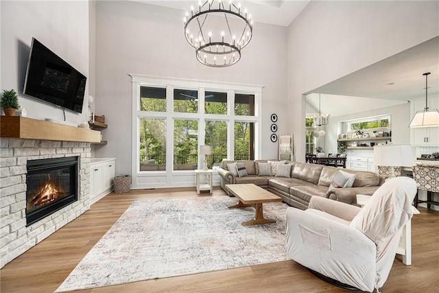 21143 W 189th Ct, Spring Hill, KS 66083 - living room featuring a chandelier, a towering ceiling, a brick fireplace, and wood finished floors