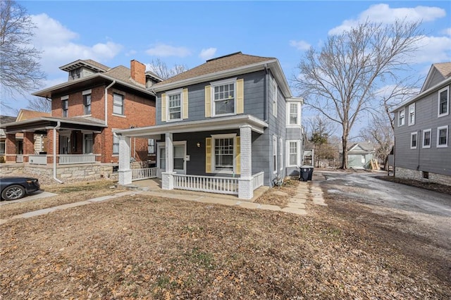 american foursquare style home featuring covered porch and driveway