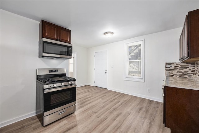 kitchen with light countertops, light wood-style flooring, backsplash, and stainless steel appliances