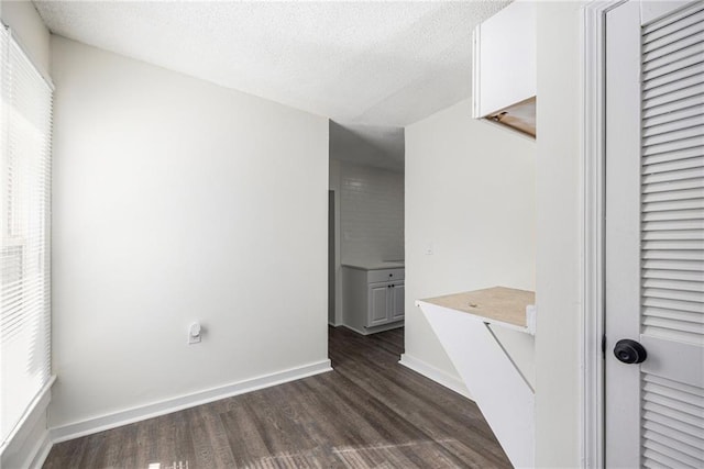 interior space with baseboards, a textured ceiling, and wood finished floors