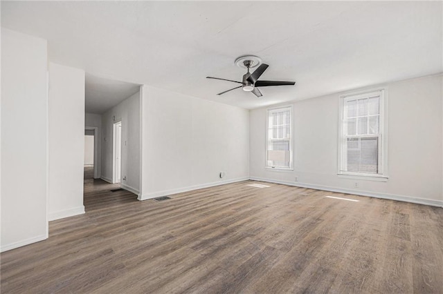 spare room featuring a ceiling fan, wood finished floors, visible vents, and baseboards