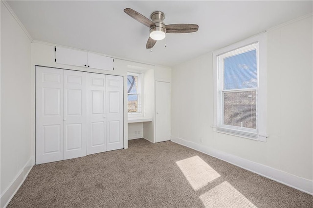 unfurnished bedroom with a closet, carpet flooring, ceiling fan, and baseboards