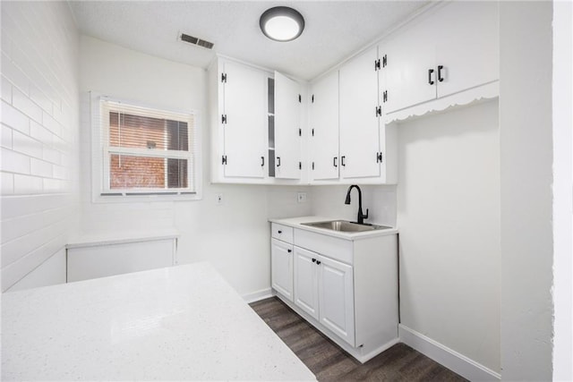 kitchen featuring a sink, white cabinetry, dark wood-style flooring, and light countertops