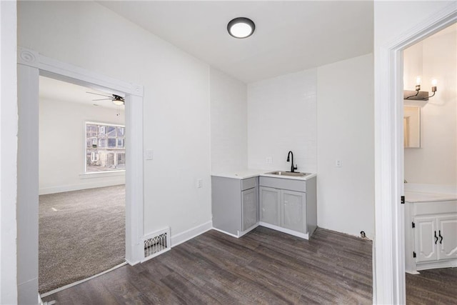 clothes washing area featuring a sink, visible vents, baseboards, and dark wood-style floors