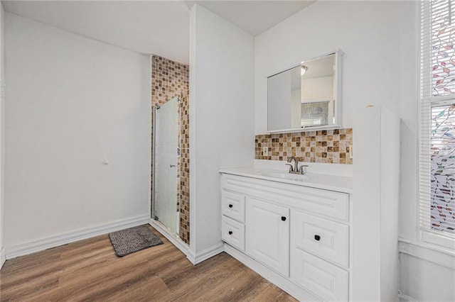 full bath featuring tasteful backsplash, vanity, wood finished floors, and a shower stall