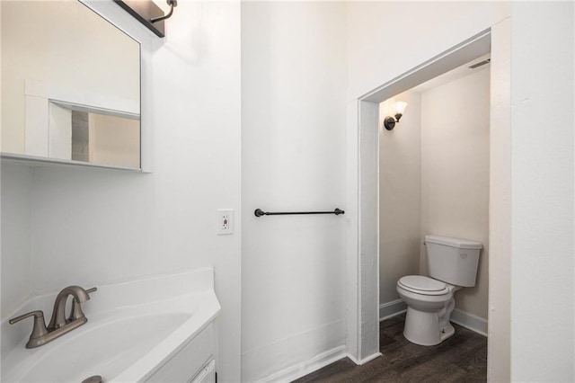 bathroom with toilet, vanity, baseboards, and wood finished floors