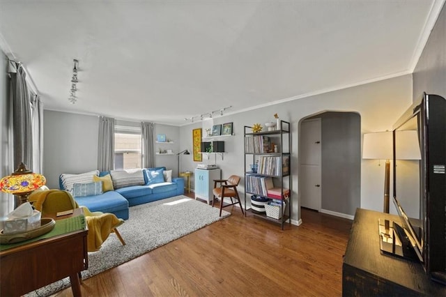 living area featuring arched walkways, rail lighting, crown molding, and wood finished floors