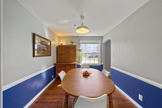 dining room with arched walkways, dark wood-style floors, and baseboards