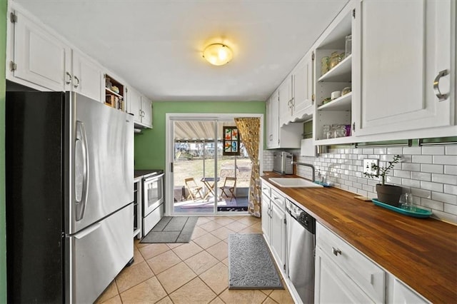 kitchen with light tile patterned floors, open shelves, butcher block countertops, decorative backsplash, and stainless steel appliances