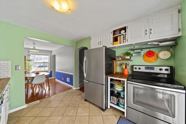 kitchen with visible vents, arched walkways, appliances with stainless steel finishes, light tile patterned flooring, and white cabinets