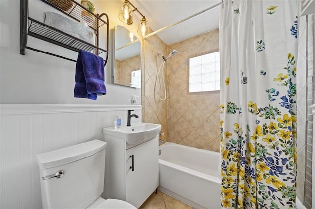 bathroom with tile patterned flooring, a wainscoted wall, toilet, shower / tub combo, and vanity