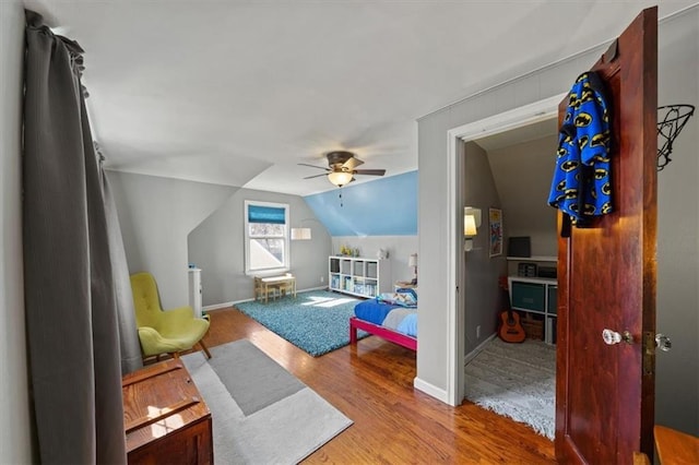 bedroom featuring a ceiling fan, vaulted ceiling, wood finished floors, and baseboards