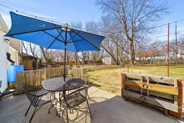 view of patio with a storage shed, an outbuilding, outdoor dining space, and fence