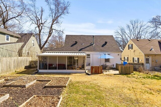 rear view of house with a lawn, a sunroom, a fenced backyard, and a garden