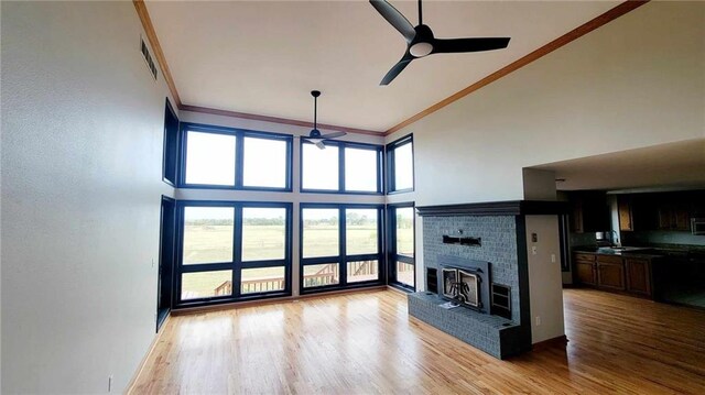 unfurnished living room featuring a fireplace, wood finished floors, a ceiling fan, and ornamental molding