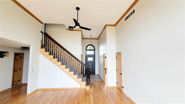 entryway with visible vents, wood finished floors, stairway, a high ceiling, and baseboards