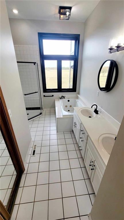 full bathroom featuring tile patterned flooring, double vanity, a whirlpool tub, and a sink