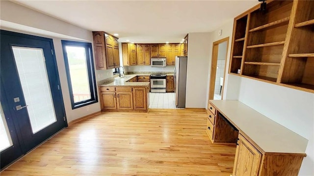 kitchen with brown cabinetry, light wood finished floors, and stainless steel appliances