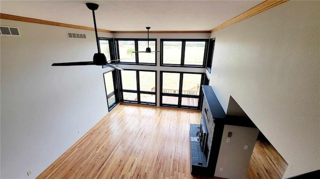 unfurnished living room featuring crown molding, wood finished floors, visible vents, and ceiling fan