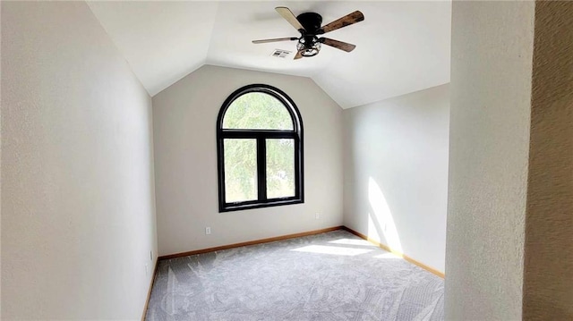 carpeted empty room featuring vaulted ceiling, baseboards, visible vents, and ceiling fan