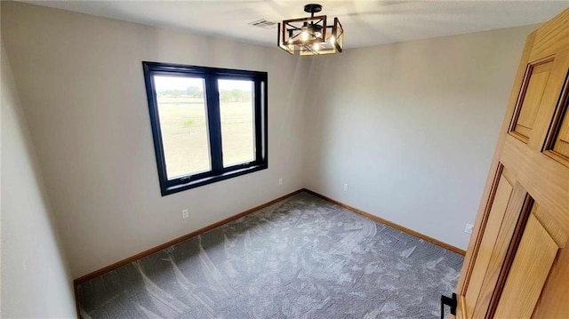 carpeted empty room featuring a notable chandelier, visible vents, and baseboards